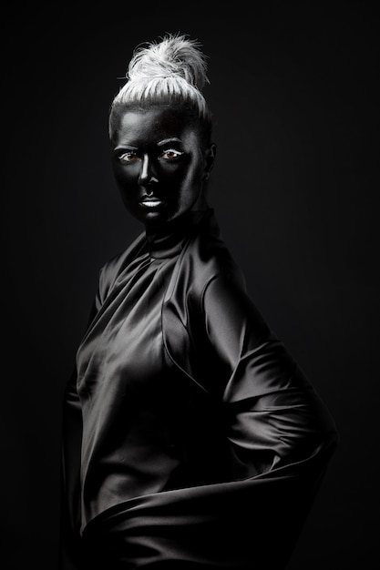 Young woman with black face paint on a black background