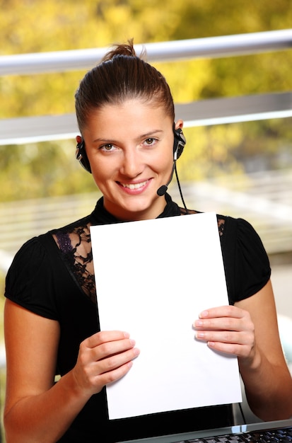 a young woman with a blank sheet of white paper working in the office