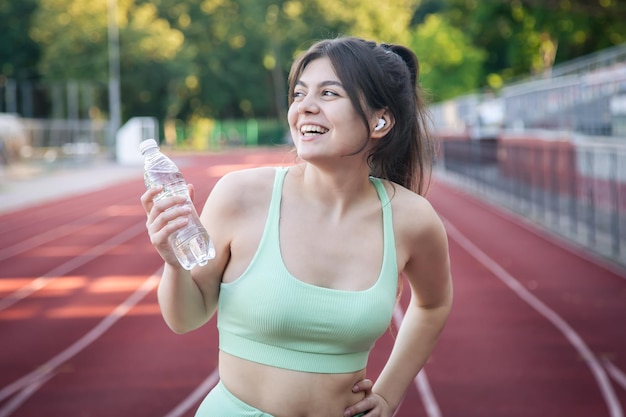 A young woman with a bottle of water in training at the stadium