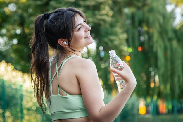 A young woman with a bottle of water in training at the stadium