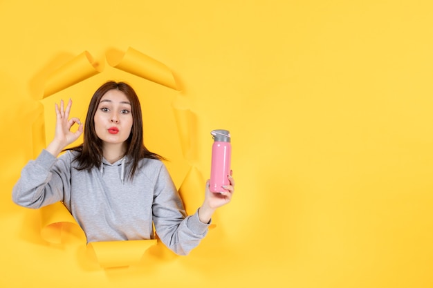 young woman with bottle of water on yellow paper background athletes gym fit indoor