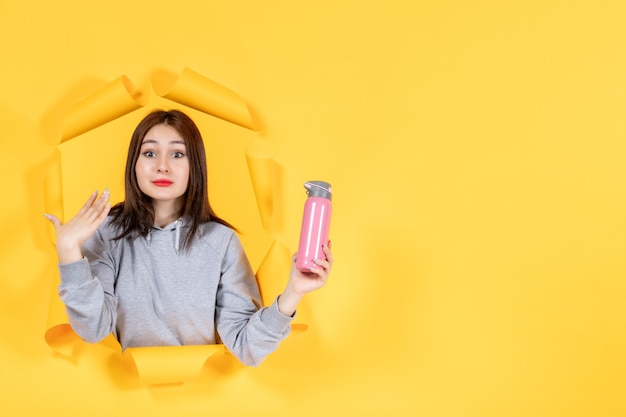 young woman with bottle of water on yellow paper background fit athlete indoor gym