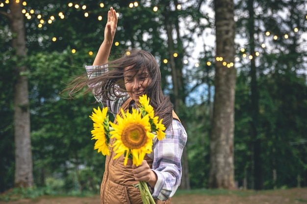 A young woman with a bouquet of sunflowers on a blurred background in nature