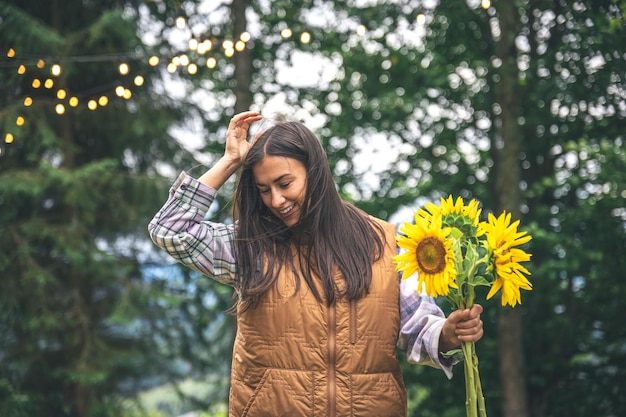 A young woman with a bouquet of sunflowers on a blurred background in nature