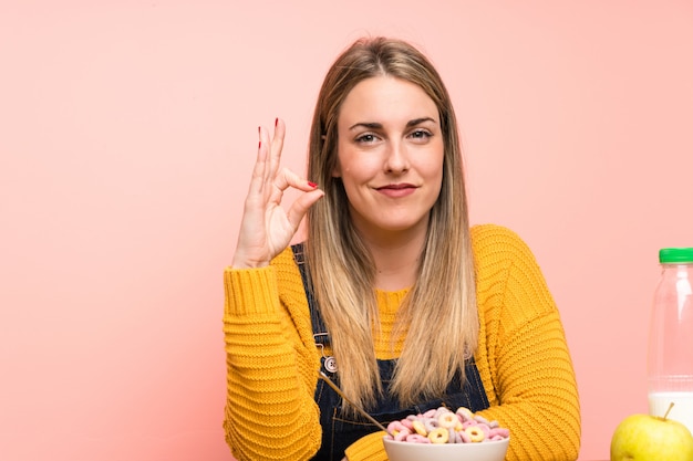 Photo young woman with bowl of cereals showing an ok sign with fingers