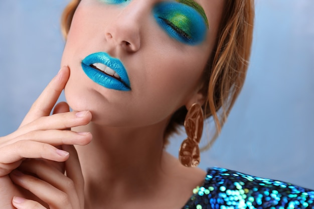 Young woman with bright green makeup on color background