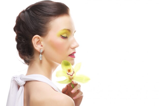 Young woman with bright make up holding orchid