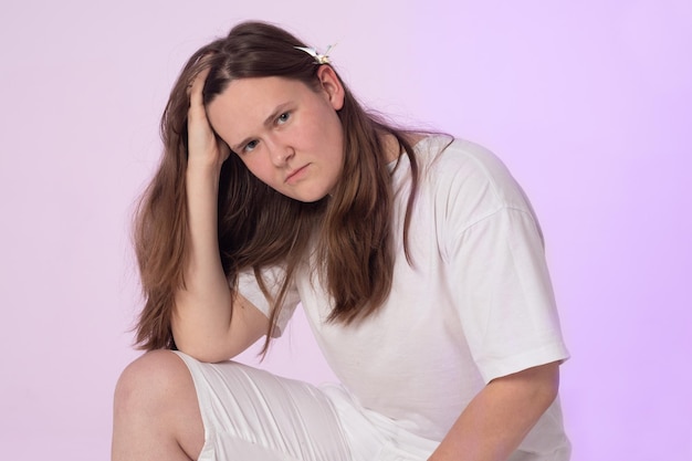 A young woman with a butterfly in hair. Woman in white clothes on a pale pink background