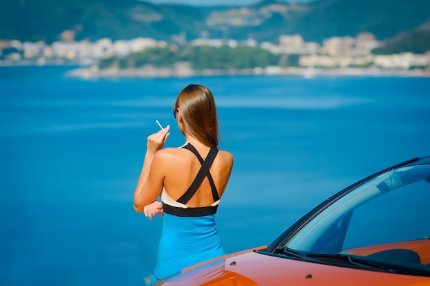 Young woman with car on sea side