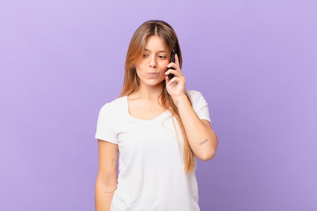 Young woman with a cell phone feeling sad, upset or angry and looking to the side