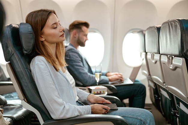 Young woman with cellphone resting in airplane