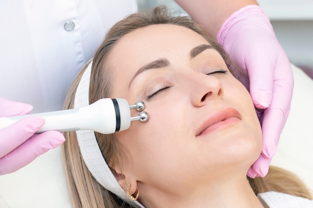 young woman with closed eyes receiving rf lifting procedure in beauty salon.