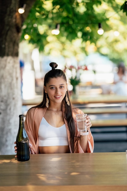 Young woman with a cold drink sitting in a cafe on the street