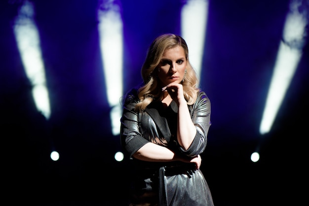 Young woman with colorful lights on concert on the stage.