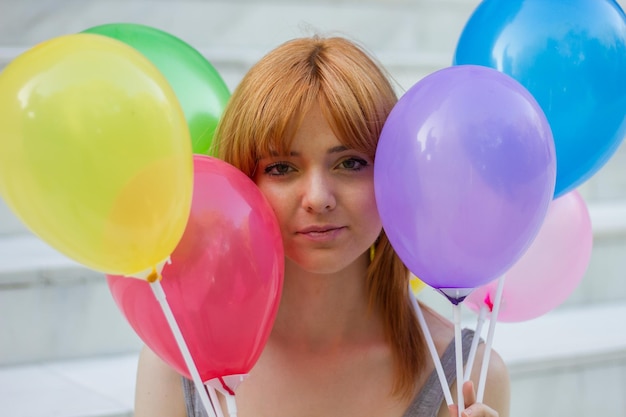 Young woman with coloured balloons in park