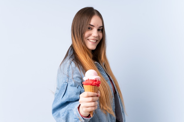 Young woman with a cornet ice cream isolated on blue wall with happy expression