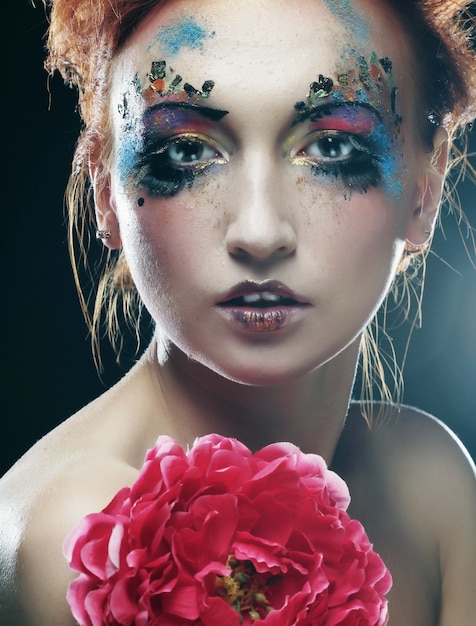 Photo young woman with creative make up holding big pink flower