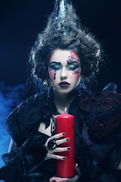 Young woman with creative make up holding candle Halloween theme