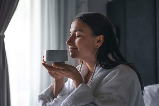 A young woman with a cup of coffee in bed