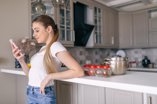 Young woman with cup of coffee is stare at the phone at kitchen