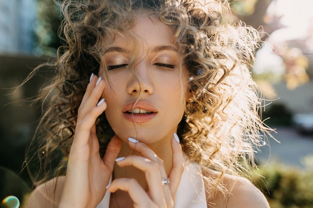 Young woman with curly hair and closed eyes