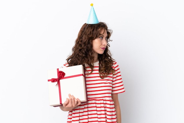 Young woman with curly hair holding present isolated on white background looking to the side