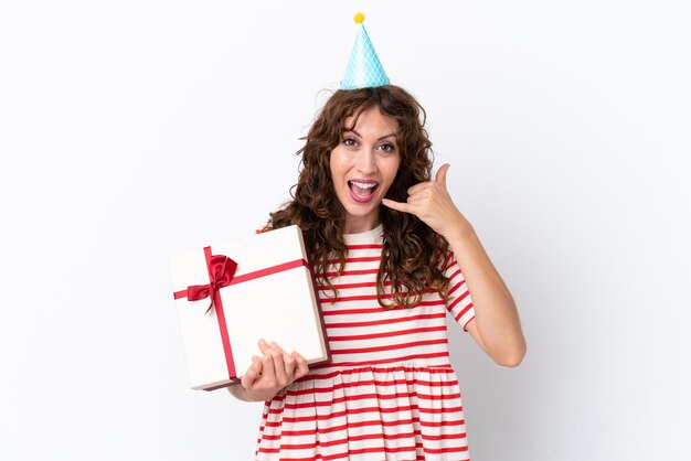 Young woman with curly hair holding present isolated on white background making phone gesture Call me back sign