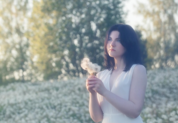 Young woman with dandelion in park