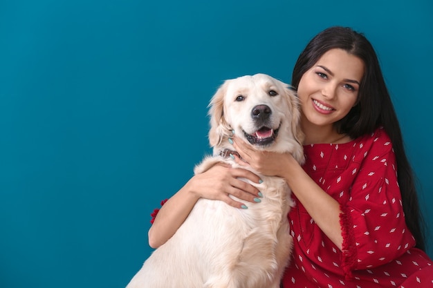 Young woman with dog on color background. Friendship between pet and owner