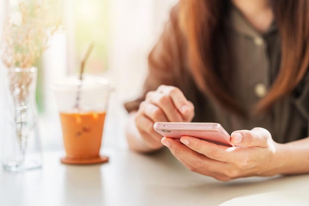 Young woman with drinks using mobile phone and relaxing in cafe Modern lifestyle