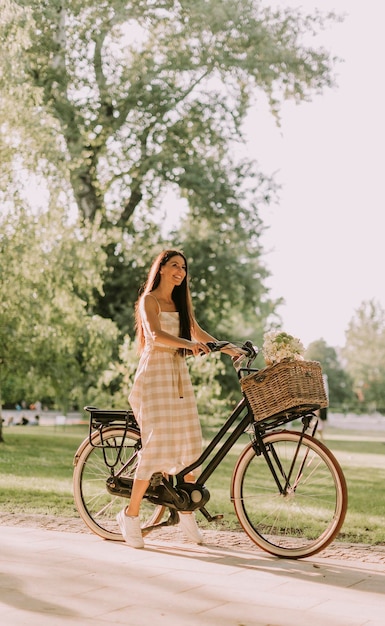 Young woman with electric bike and flowers in the basket