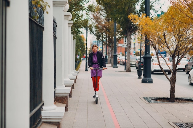 Young woman with electric scooter at the city