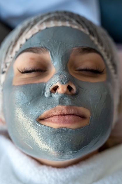 Young woman with a face mask lying on a bed in a beauty clinic