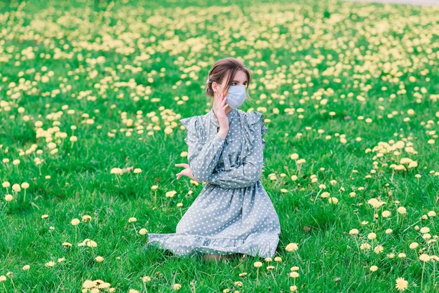 Young woman with face mask outdoors in a blossom garden. Corona virus concept.