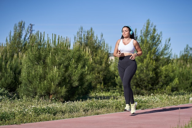 Young woman with fit body running. Female model in sportswear exercising and headphones