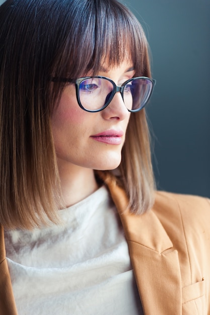 young woman with glasses, dressed as casual on gray