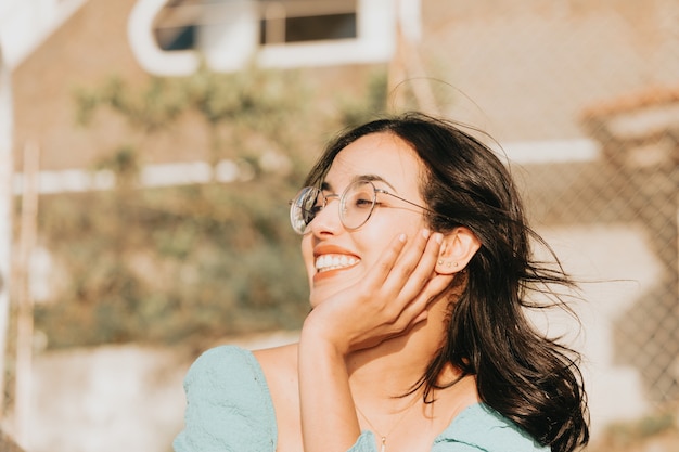 Young woman with glasses smiling to camera during a super sunny day 