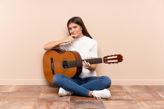 Young woman with guitar sitting on the floor laughing