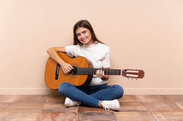 Young woman with guitar sitting on the floor