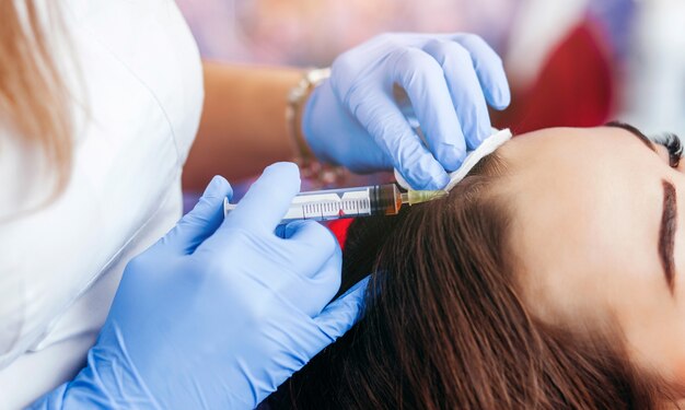 Young woman with hair loss problem receiving injection