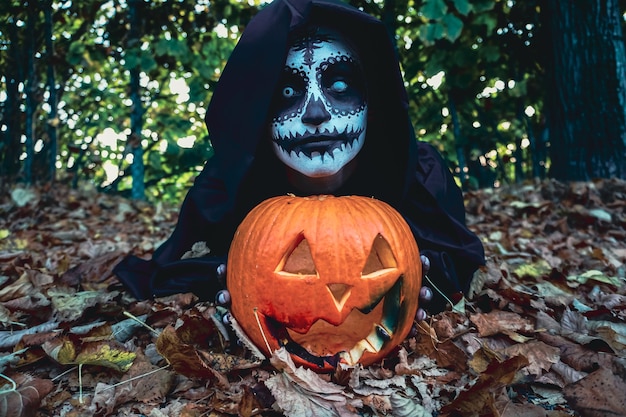 Young woman with halloween paint face mask wearing black hood