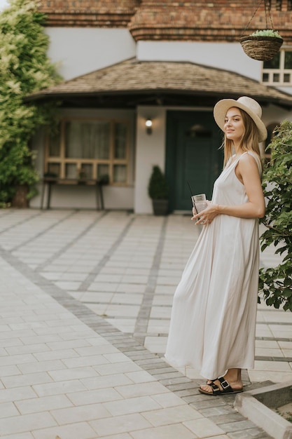 Young woman with hat drinking cold lemonade in the resort garden