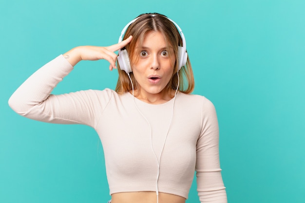 Young woman with headphones looking surprised, realizing a new thought, idea or concept