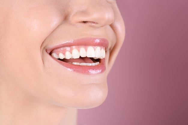 Young woman with healthy teeth and beautiful smile on color background closeup Space for text