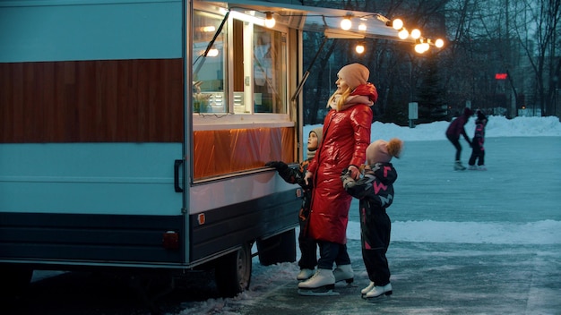 A young woman with her children walking to a little shop on skates