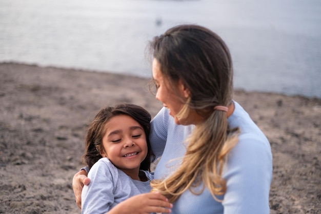 Young woman with her daughter in her arms by the sea on an afternoon walk by the sea Concept motherhood lifestyle children