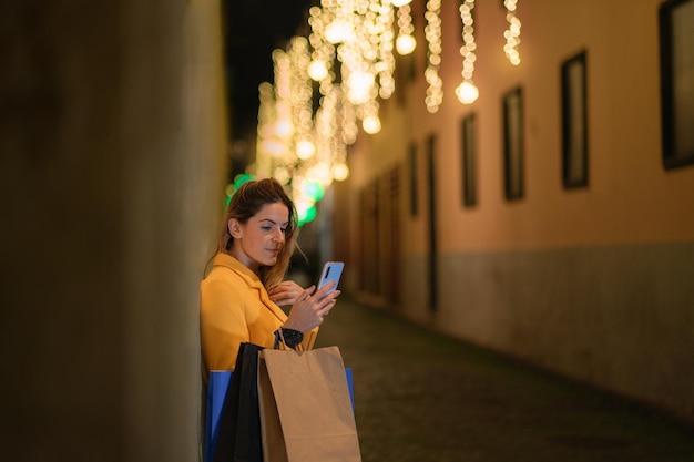 Young woman with her smartphone sharing her Christmas purchases on social networks