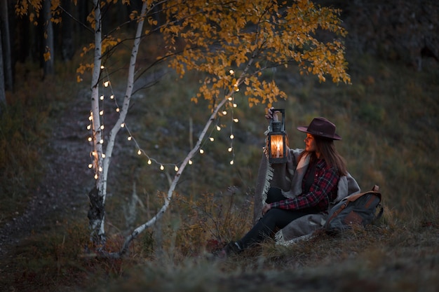 Young woman with a kerosene lamp in the forest