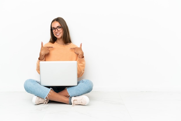 Young woman with a laptop sitting on the floor proud and self-satisfied