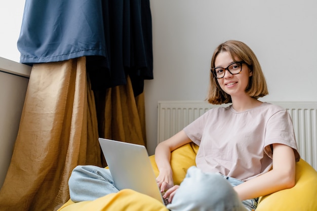 Young woman with laptop working online in the apartment